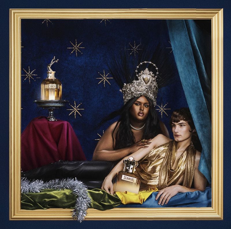 Two models posed within a golden picture frame against a dark blue starred backdrop for Jean Paul Gaultier fragrance