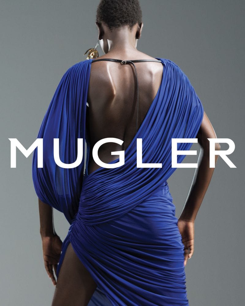 Model in royal blue dress with open back standing against a grey studio backdrop for Mugler spring 2025 ad campaign