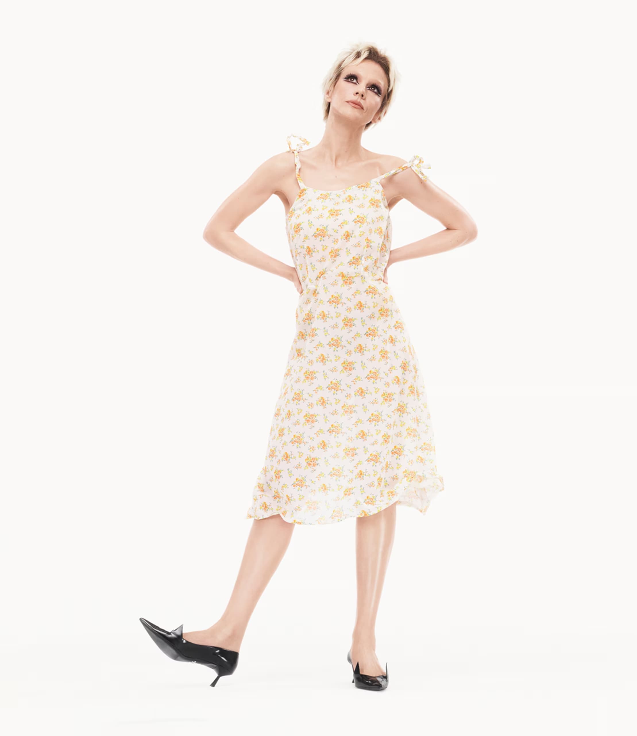Carey Mulligan in a floral dress and black heels posing against a bright white background for Prada Spring 2025 campaign.