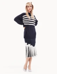Carey Mulligan wearing a navy striped sweater and fringed skirt against a white studio background