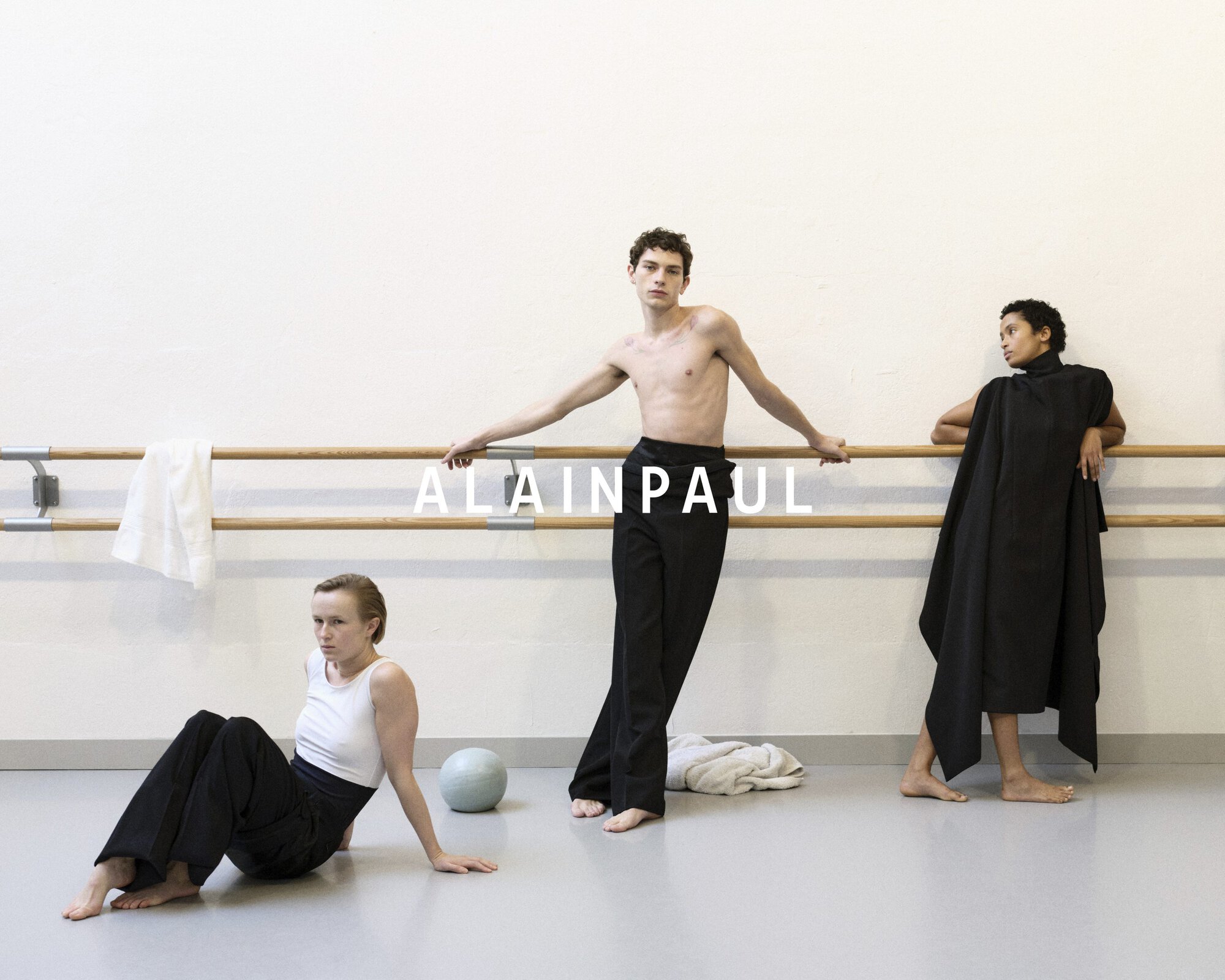 Three models posing near a wooden ballet barre in a studio setting for Alainpaul fall 2024 campaign