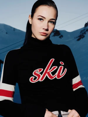 Model wearing a black turtleneck with red ski branding against a snowy mountain backdrop