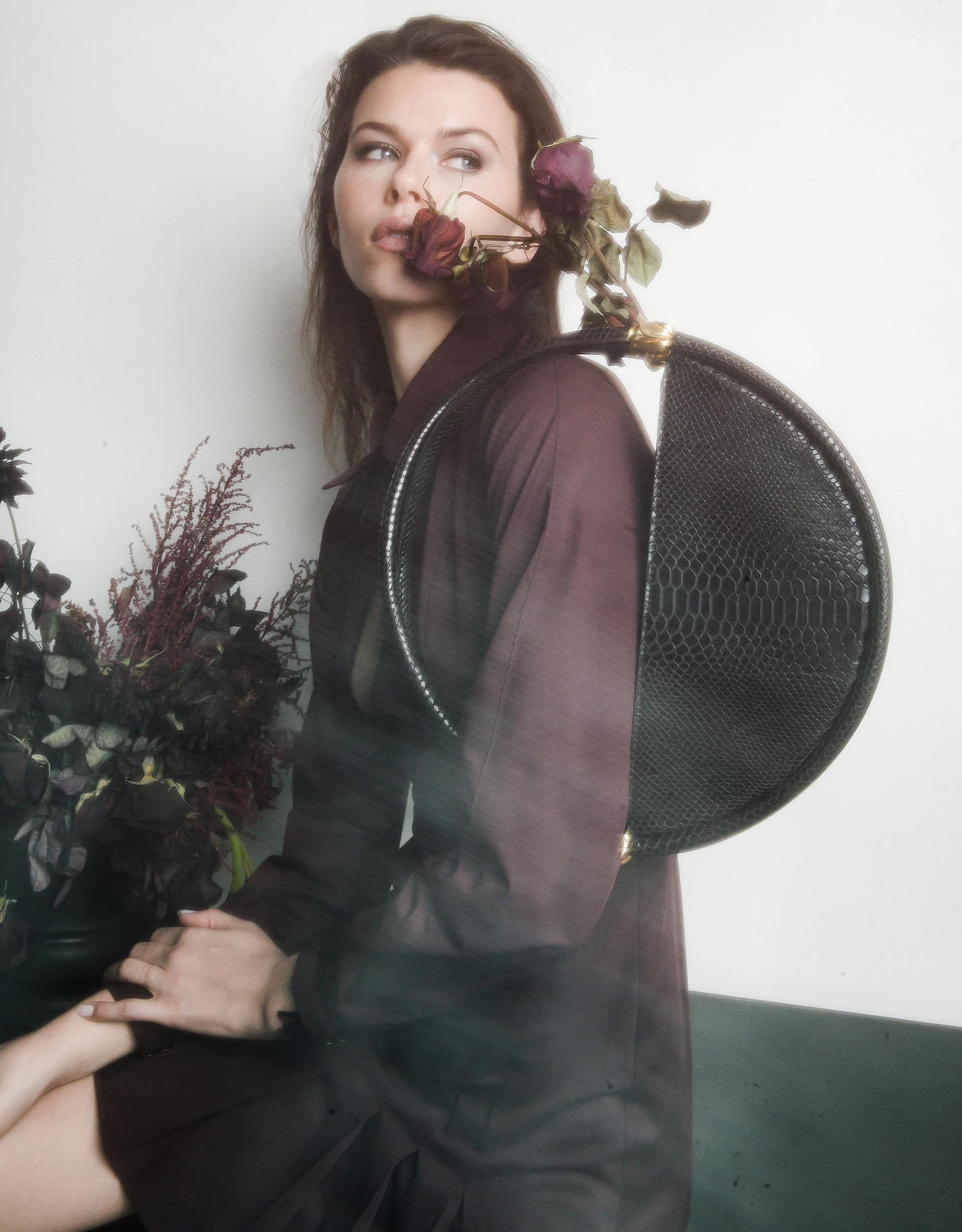 Georgia Fowler holding a large circular black handbag and dried roses for Contessa Mills