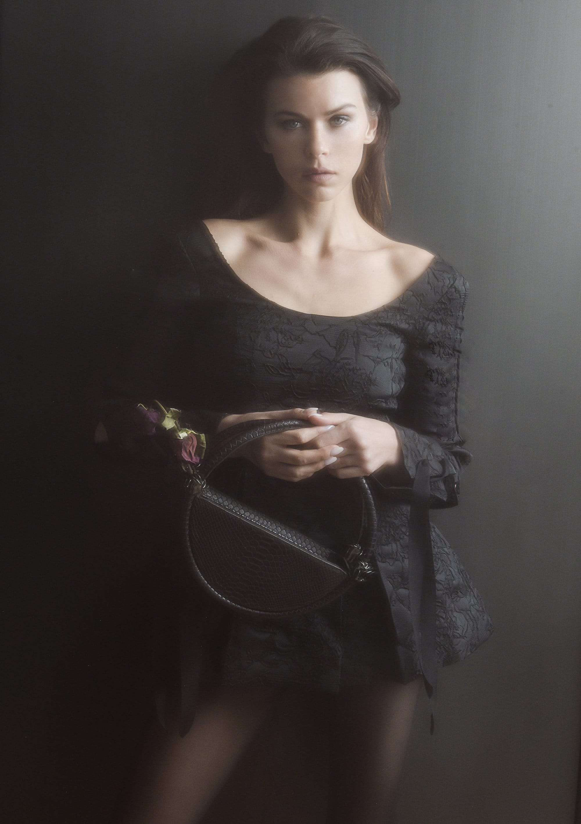 Model Georgia Fowler holding a round black handbag in a campaign portrait for Contessa Mills World Bag 2024.