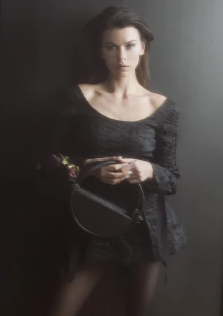 Model Georgia Fowler holding a round black handbag in a campaign portrait for Contessa Mills World Bag 2024.
