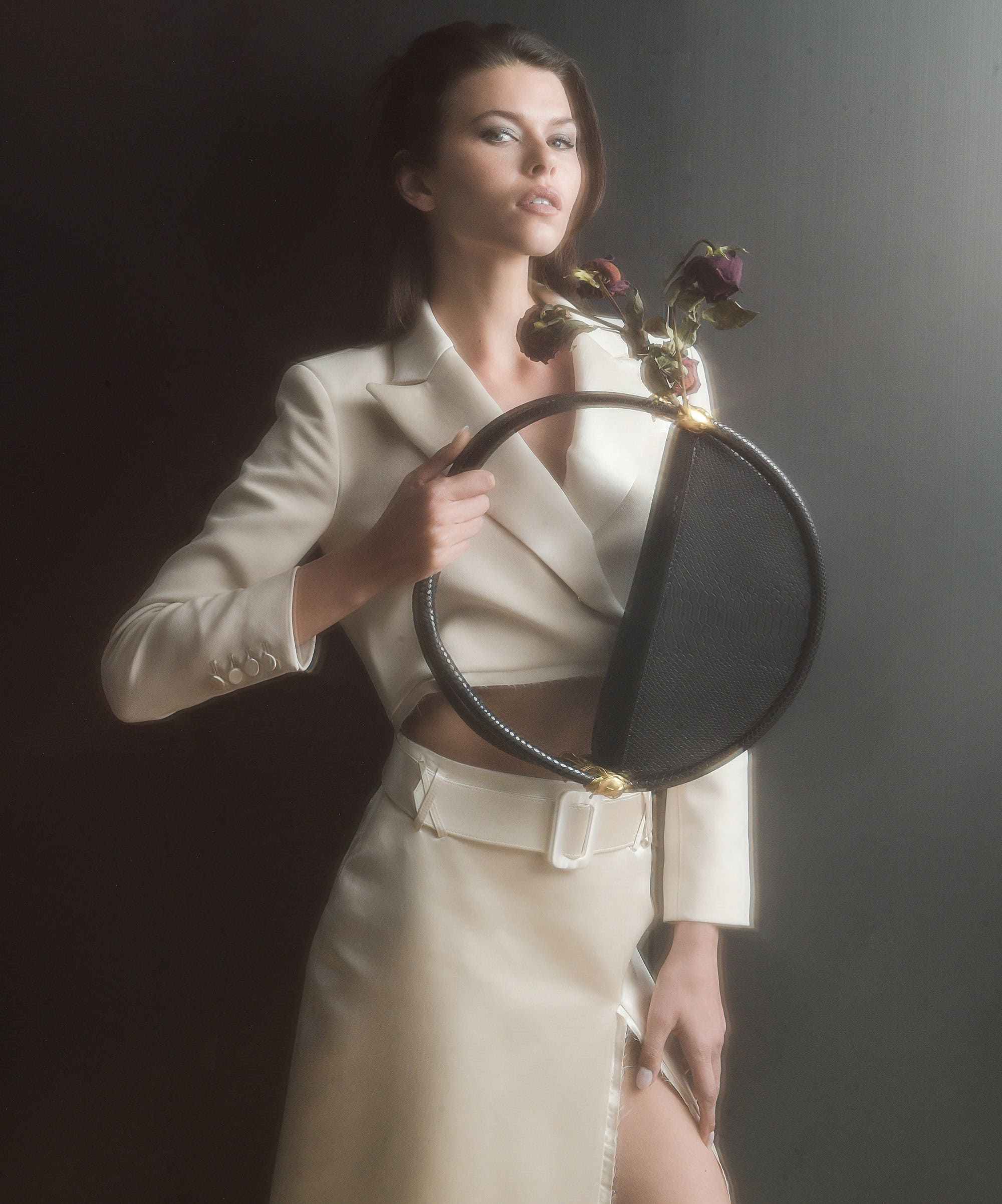 Model Georgia Fowler holding a circular black handbag and roses for Contessa Mills World Bag campaign