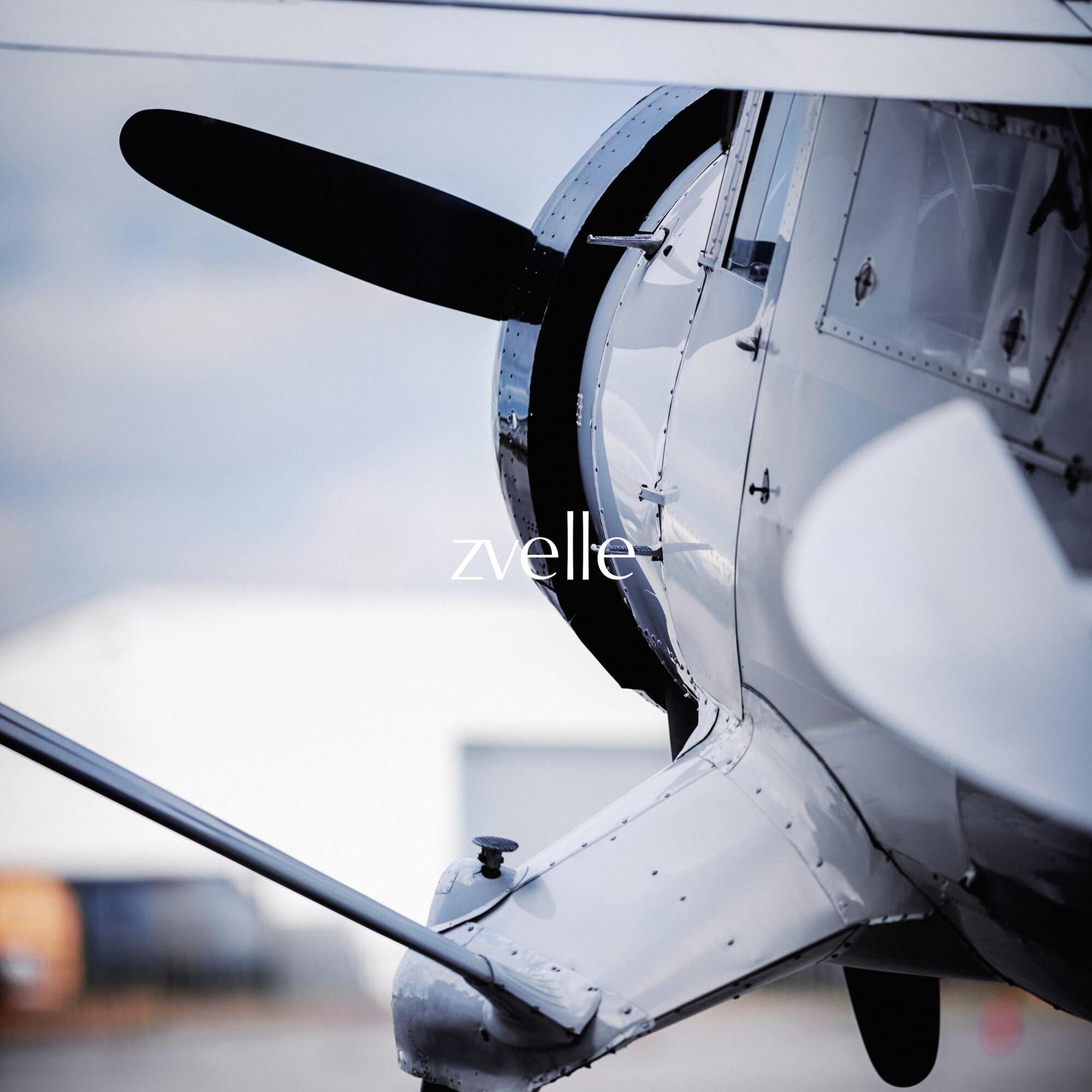Close-up of a white vintage airplane propeller and engine cowl with the brand name zvelle superimposed