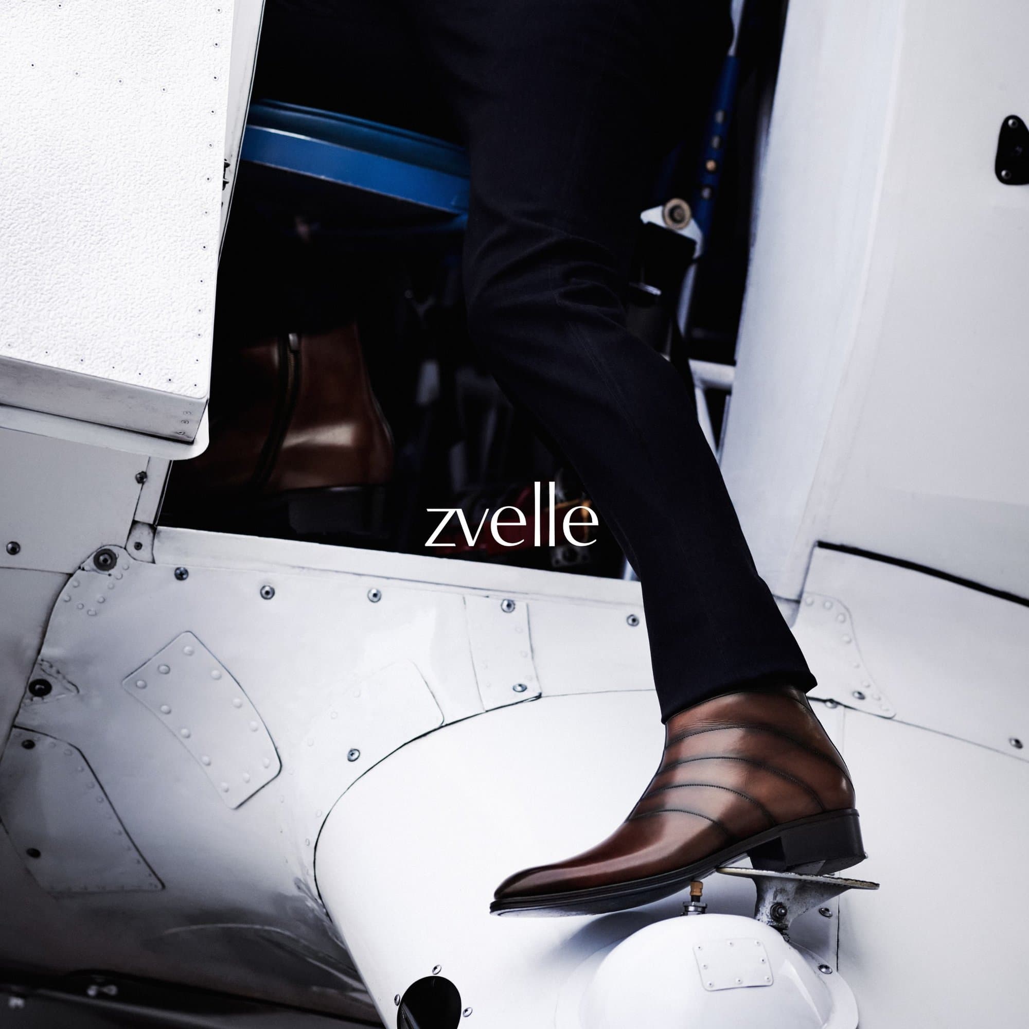 Close-up of a person wearing brown leather boots and black trousers stepping out of a white aircraft door.