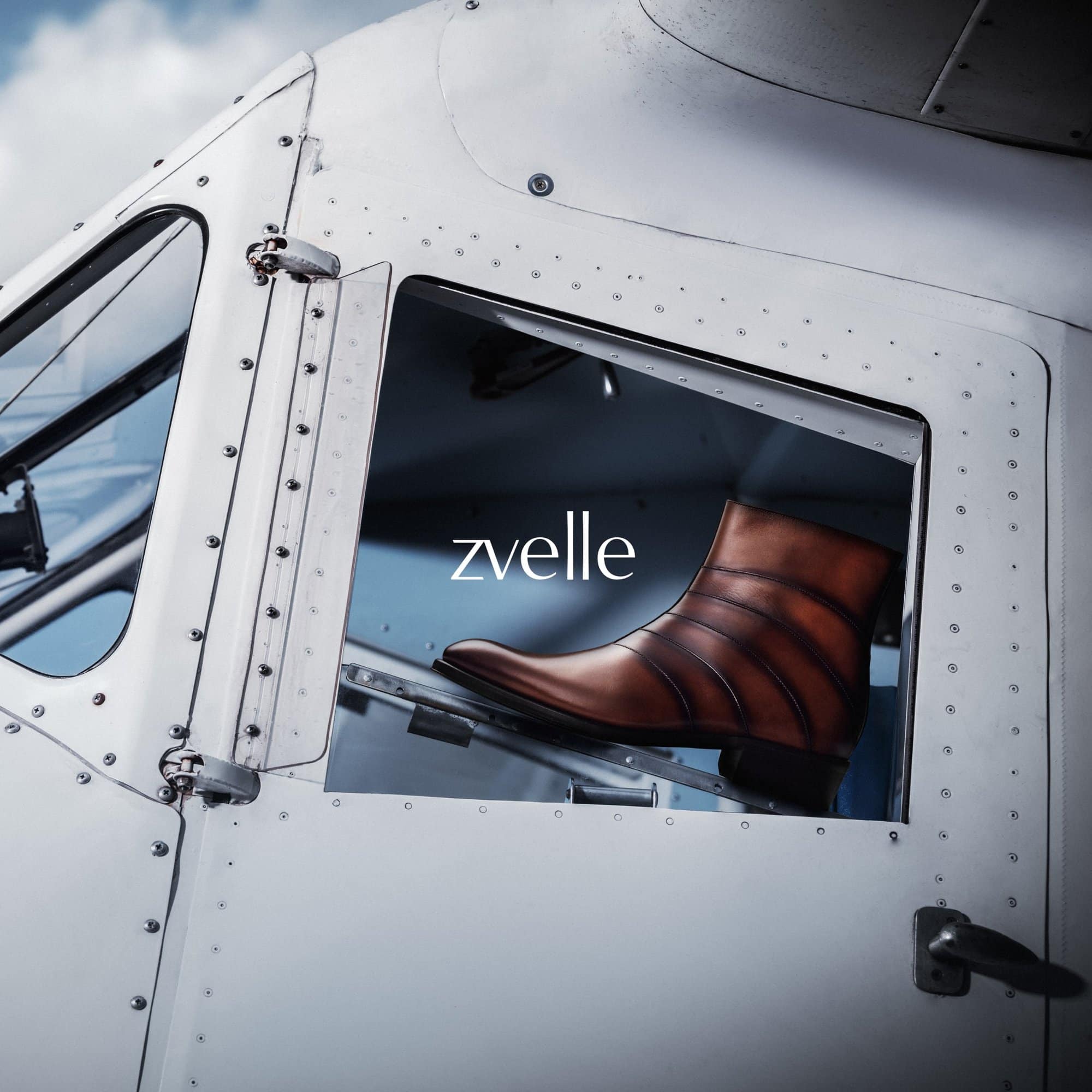 Brown leather boot displayed on the exterior step of a white aircraft cabin door with visible rivets