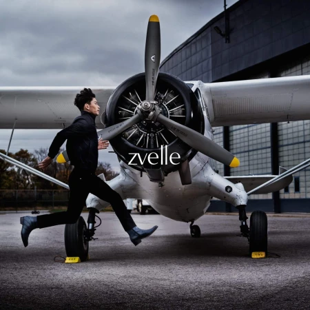 Man running past a parked vintage white airplane on an outdoor tarmac for the Zvelle Alatus campaign.