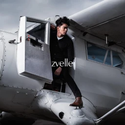 Man wearing black shirt and brown leather boots stepping out of a white aircraft door.