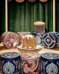 Panettone and pandoro cakes arranged with decorative patterned gift boxes against a green curtain background
