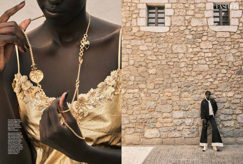 Fashion editorial featuring a dark-skinned woman in a gold floral-applique dress with gold jewelry, posed in front of a stone wall.
