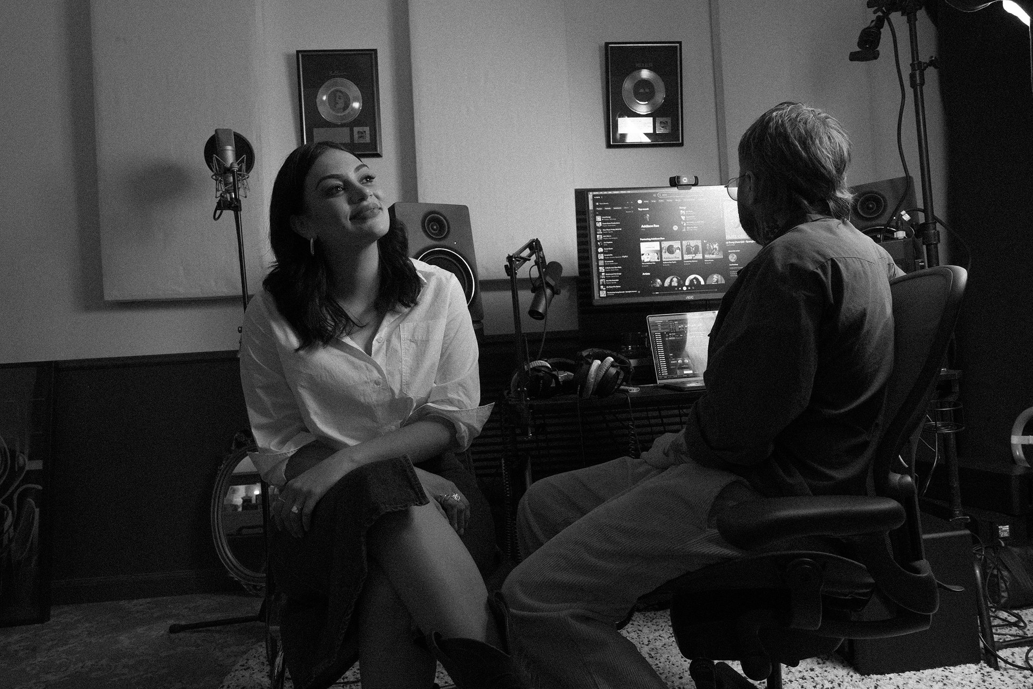 Thelma Plum seated in a recording studio with a producer in a black and white campaign image for R.M. Williams.