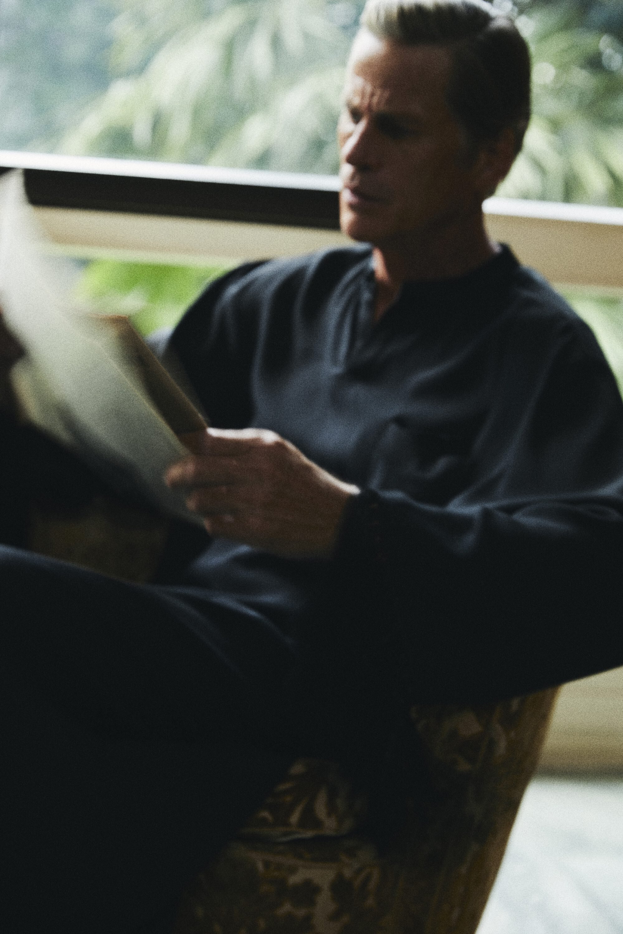 Mark Vanderloo seated in an armchair reading a newspaper for the Taller Marmo ad campaign captured by Francesco Scotti