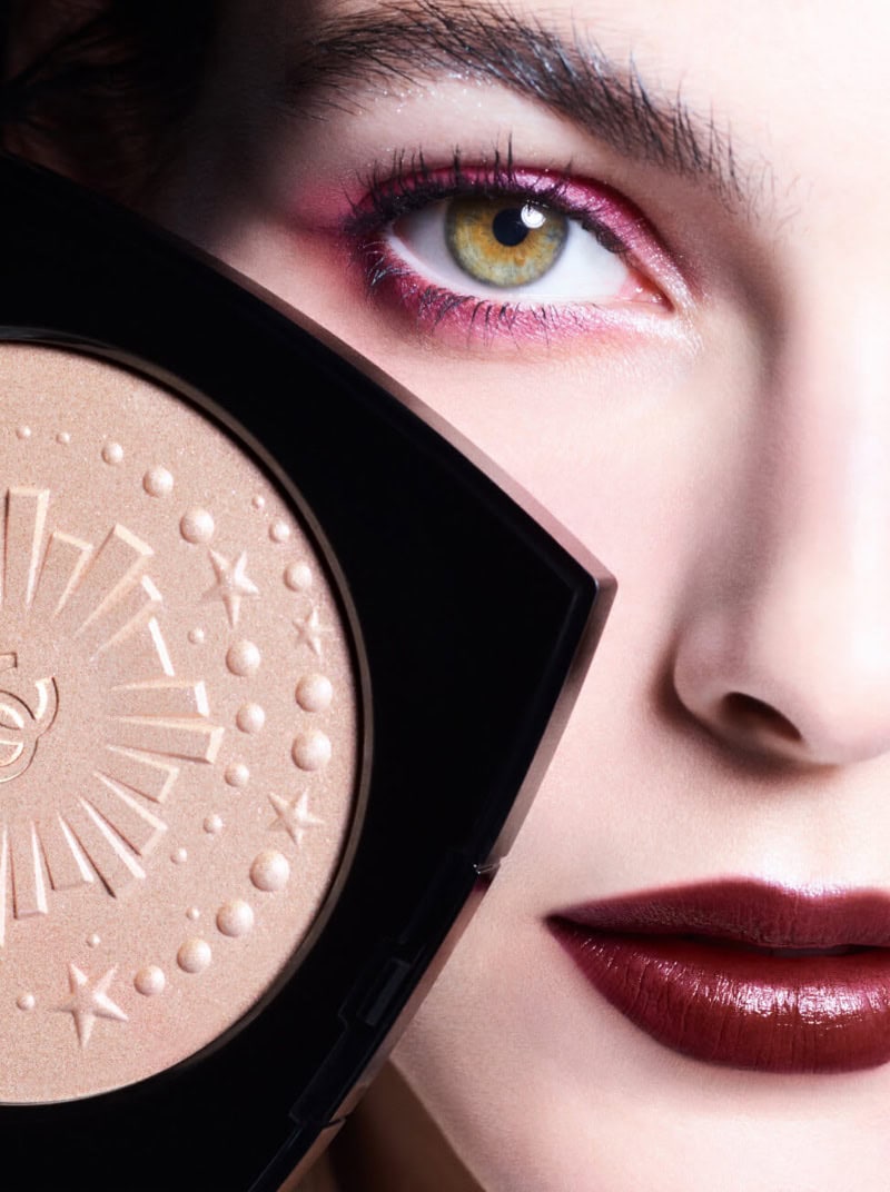Close-up portrait of model Vittoria Ceretti holding a gold embossed compact powder near her face for Chanel