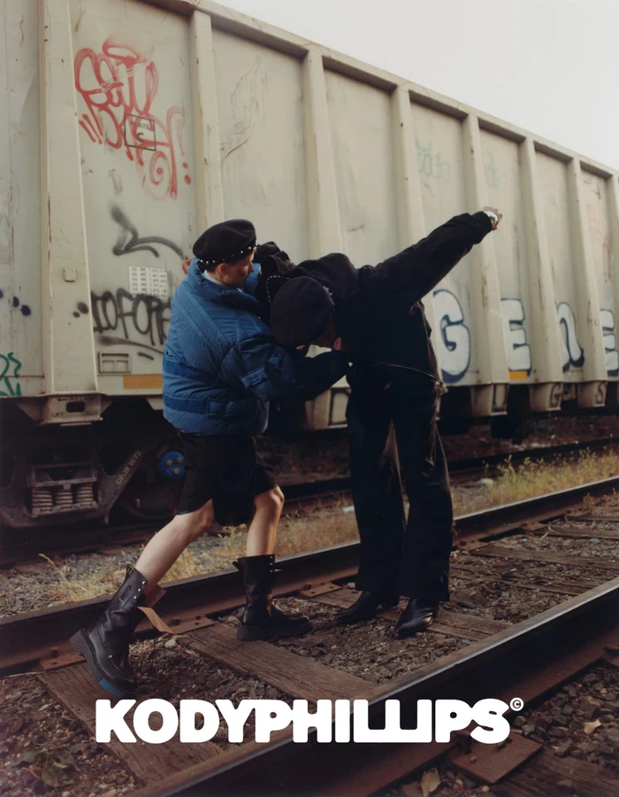 Two models posing on railroad tracks in front of a freight car for Kody Phillips
