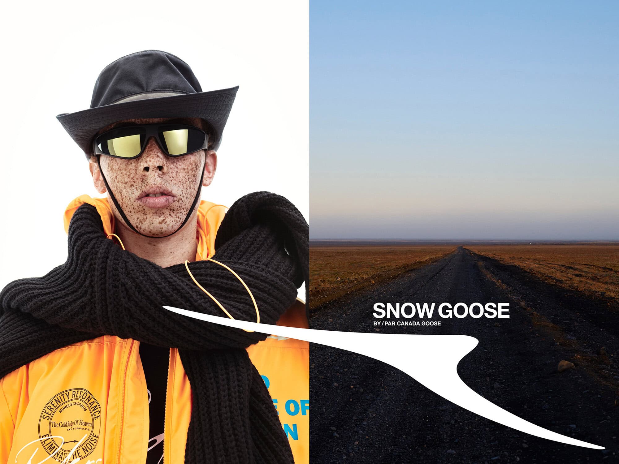 Model wearing dark reflective sunglasses, black hat, orange jacket, and thick black scarf against a road landscape background.