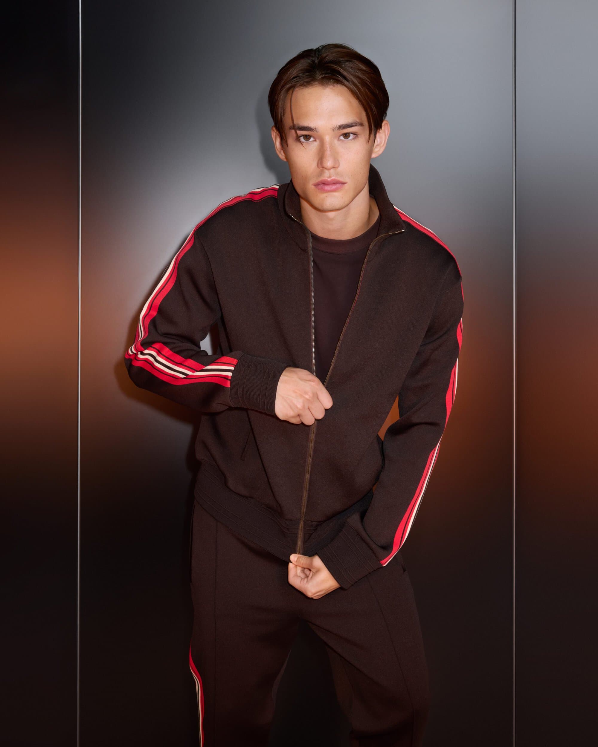 Man wearing a dark brown track jacket with red stripe details against a smooth dark background for Burberry Year of the Snake campaign