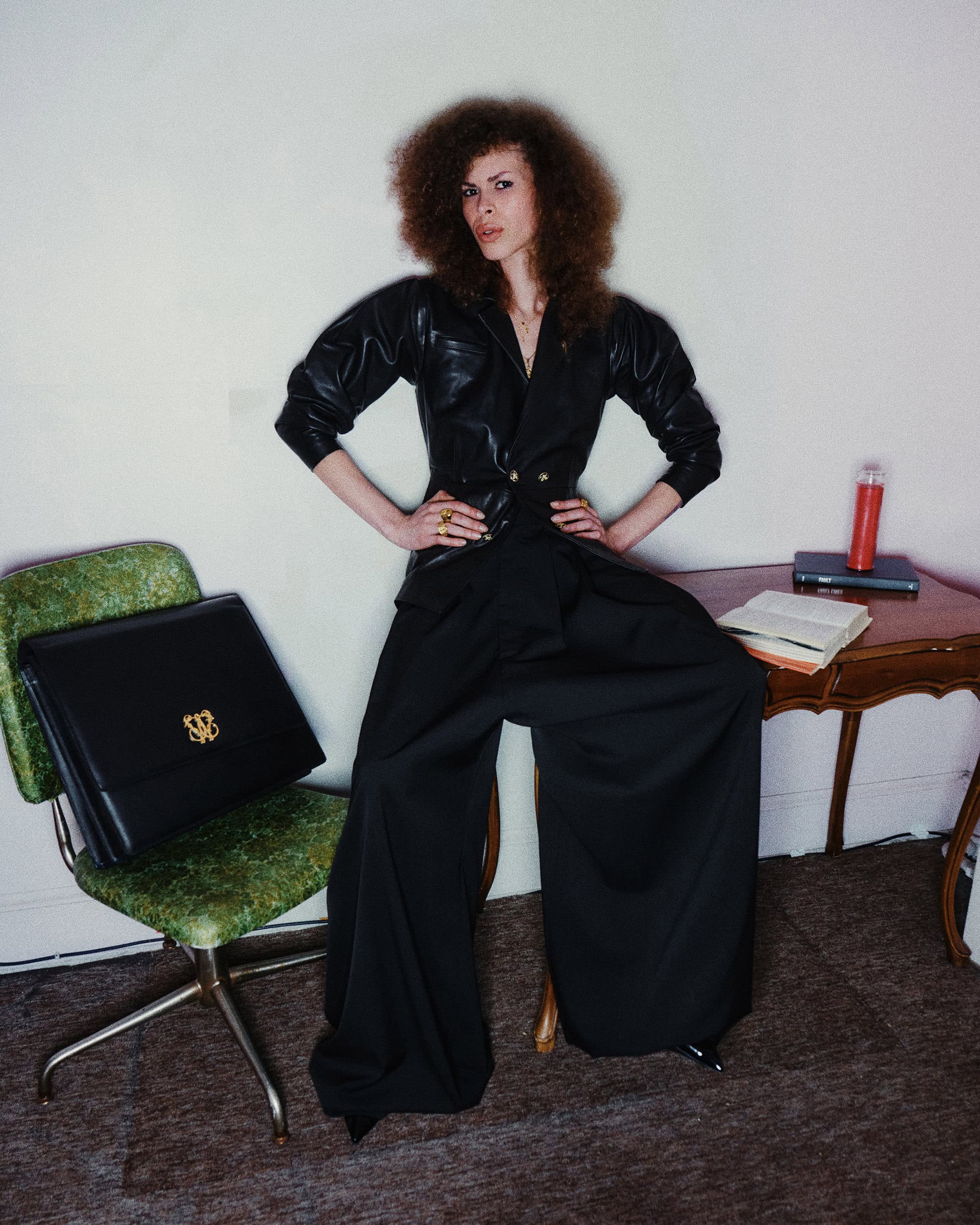 Model in black leather jacket and wide trousers posing indoors for Willy Chavarria Fall 2024 ad campaign