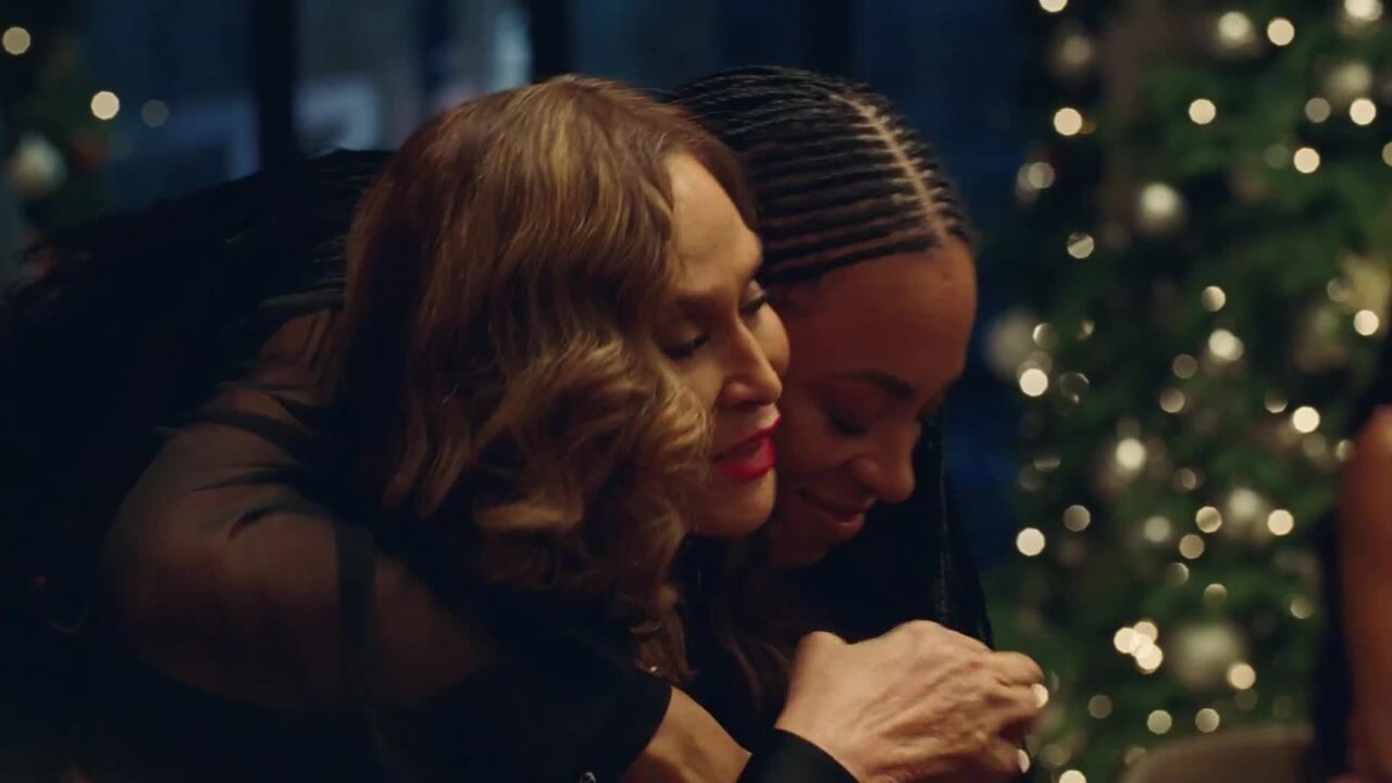 Two women embracing warmly indoors with a softly lit holiday tree and bokeh background for Gucci campaign