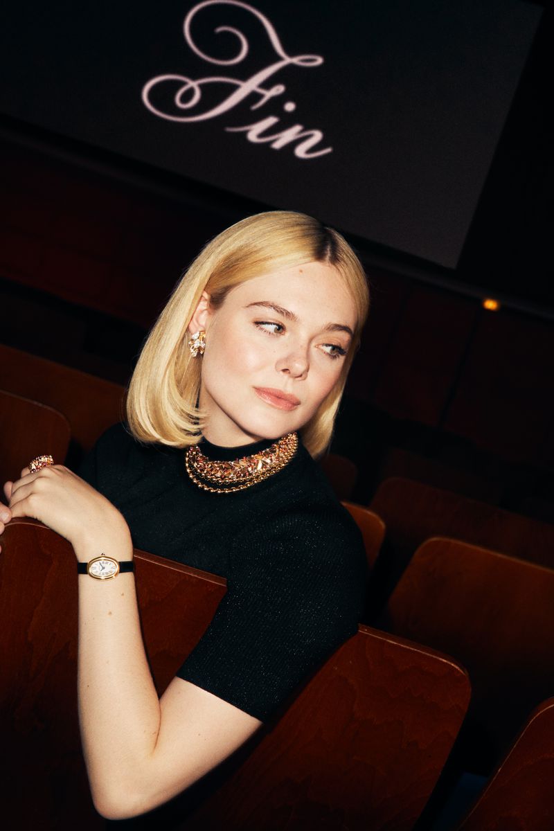 Elle Fanning wearing a statement necklace and gold watch in a dark cinema setting for Cartier Fall 2024 ad campaign