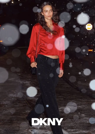 Model in red satin blouse and dark jeans walking outdoors at night with bokeh light effects for DKNY