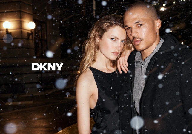 Two models standing outdoors during a snowy night for a DKNY advertising campaign shot by Christian MacDonald
