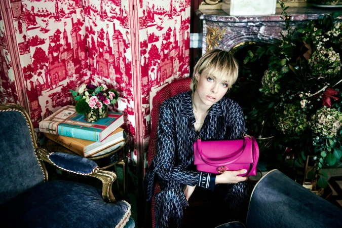 Model Edie Campbell holding a vibrant pink handbag in an ornate room for CH Carolina Herrera photographed by Norman Jean Roy
