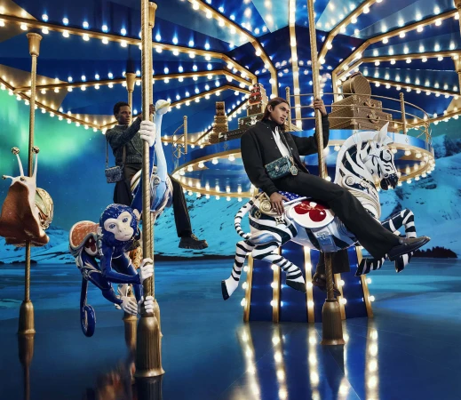 Models posing on a glowing illuminated carousel with ornate animal figures against a snowy mountain backdrop.