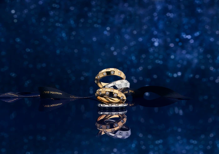 Stacked diamond rings and a black ribbon on a reflective dark blue sparkling background
