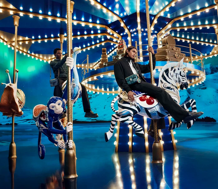 Models posing on a glowing illuminated carousel with ornate animal figures against a snowy mountain backdrop.