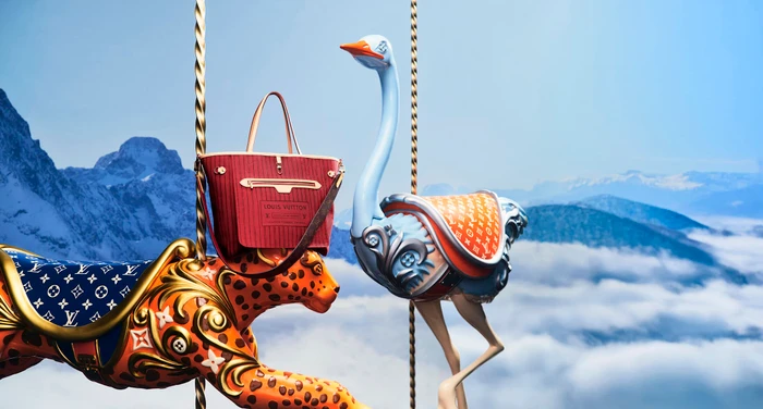 Louis Vuitton holiday campaign featuring sculpted animal carousel figures and a red handbag against a snowy mountain backdrop.