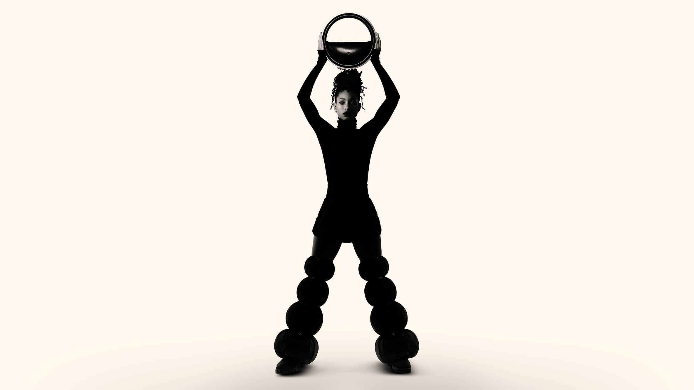 Willow Smith silhouetted against a light background holding a circular ring above head in Moncler campaign