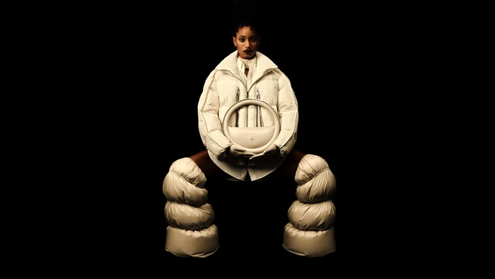 Willow Smith wearing Moncler white puffer outerwear and quilted boots against a black background