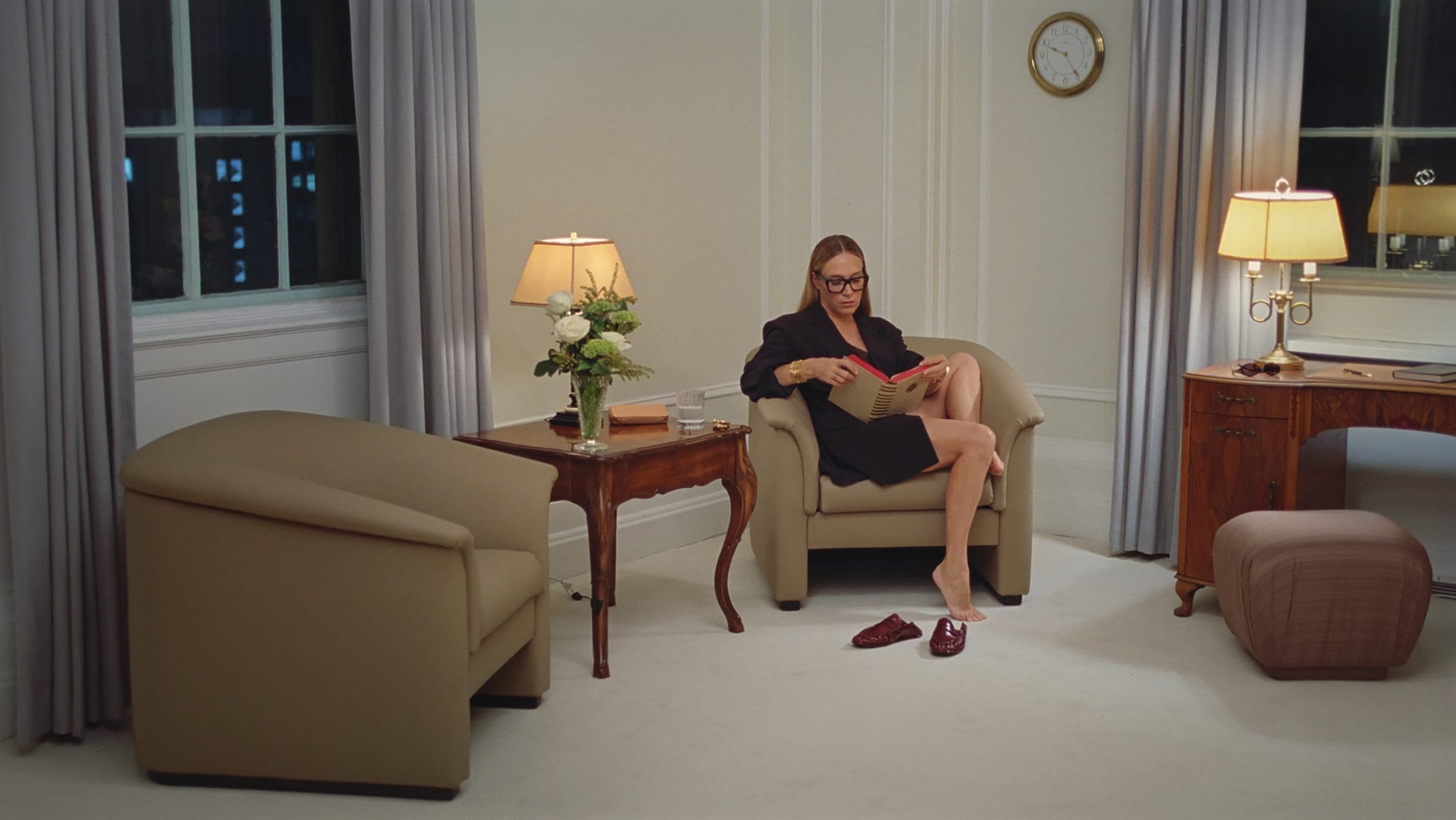 Chloe Sevigny seated in an armchair reading a book inside a room for Saint Laurent As Time Goes By campaign