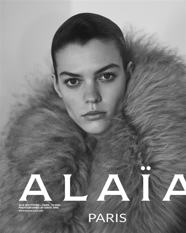 Close-up portrait of model Alix Bouthors wearing a voluminous fluffy fur collar against a neutral studio backdrop