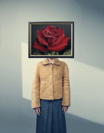 Person with a framed red rose painting in place of their head, wearing a tan shearling jacket and dark skirt.