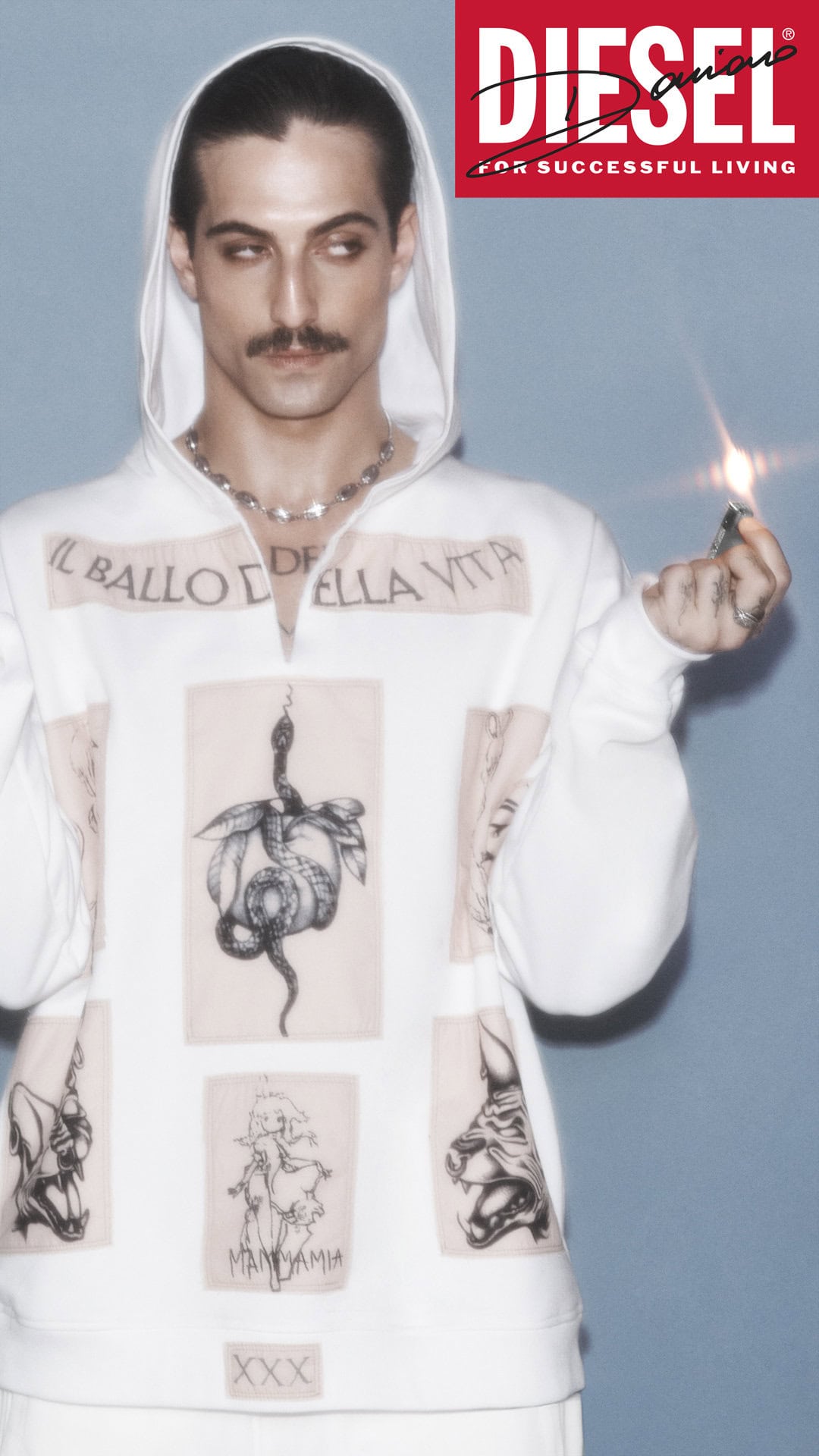 Damiano David in a white graphic hoodie holding a lit lighter against a pale blue background for Diesel