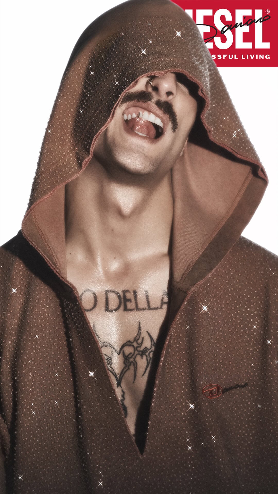 Damiano David wearing a brown hooded sweatshirt with rhinestones against a white background for Diesel Fall 2024 ad campaign.