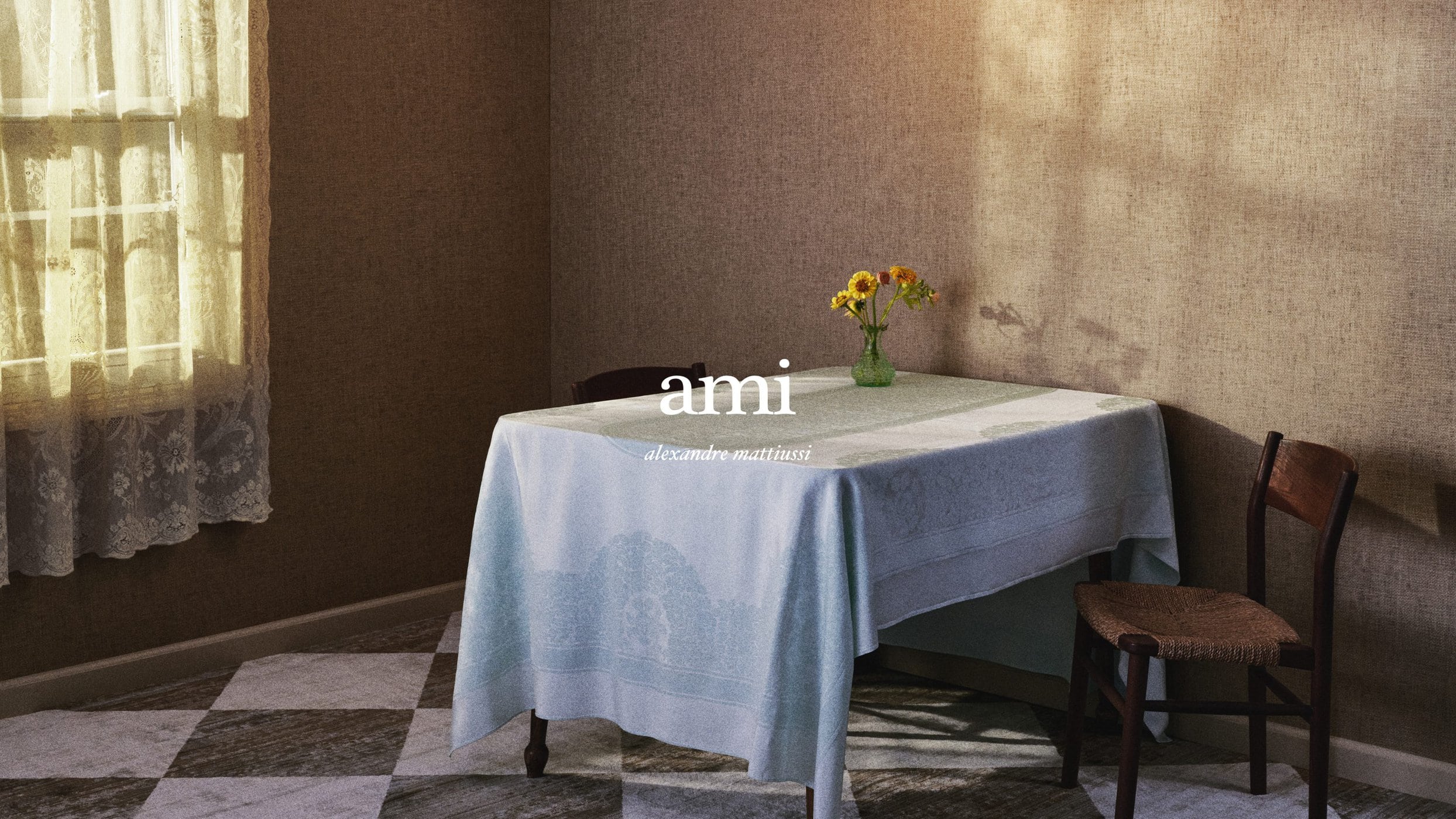 A set-dressed interior featuring a dining table with a light blue tablecloth and a small green vase of yellow flowers.
