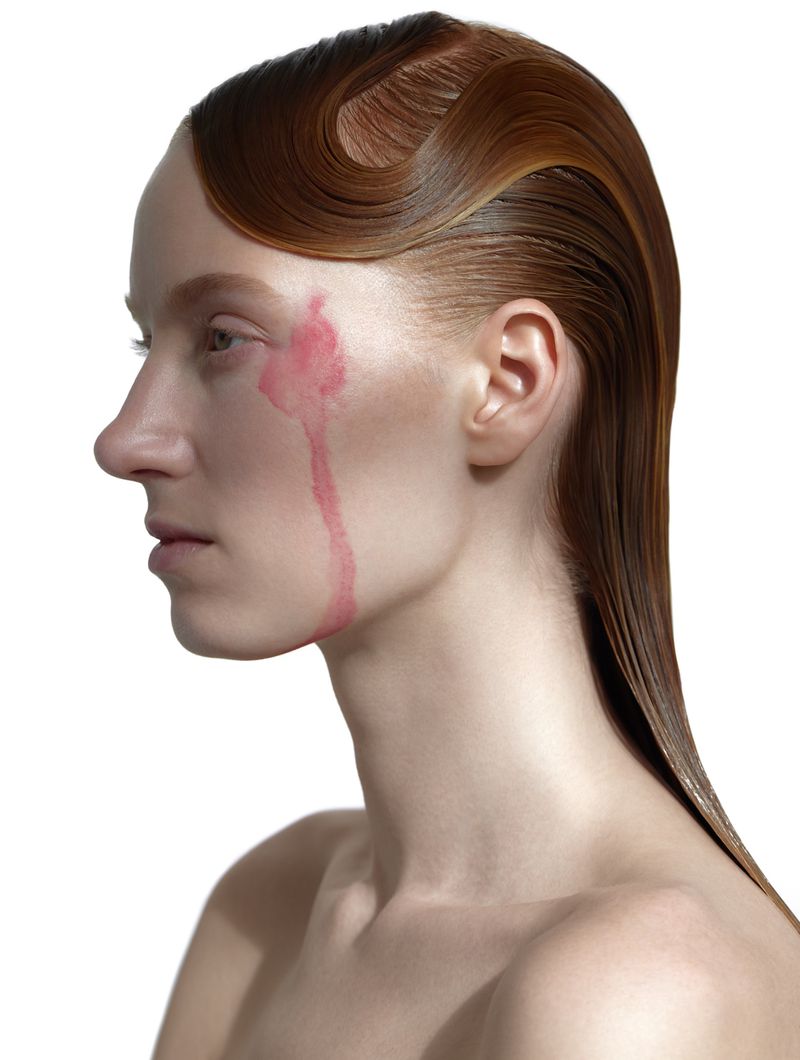 Woman with stylized red hair and skin tint in a profile view on a white background. Beauty shot for fashion or beauty editorial.
