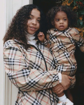 Woman holding a young child wearing matching Burberry check outfits in London for the Holiday 2024 campaign
