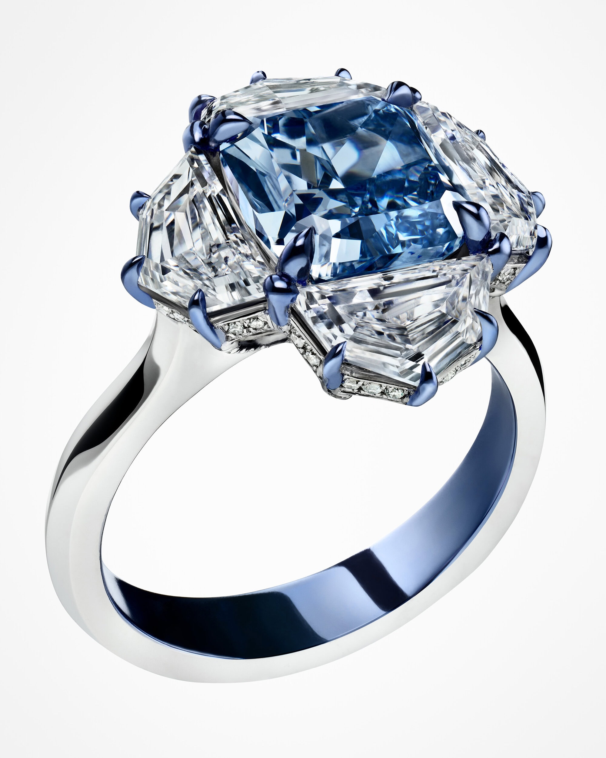 Close-up product shot of a luxury ring featuring a large blue diamond set with white side diamonds on a white background.