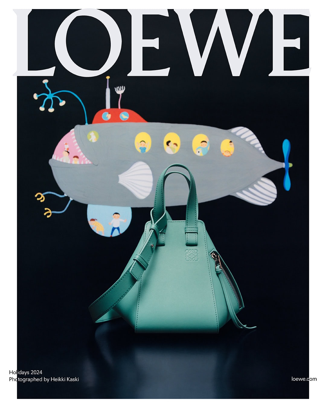 Mint green Loewe handbag resting on a dark surface against a black backdrop with an illustration of a gray submarine above.