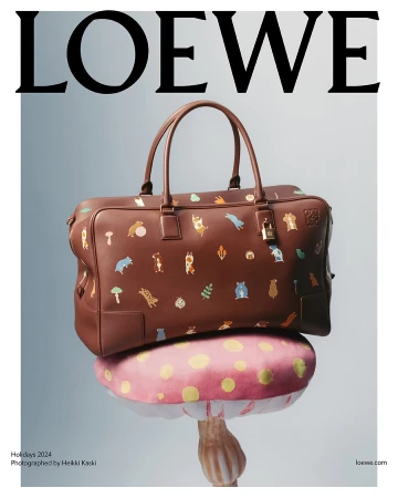Brown leather handbag with animal illustrations resting on a pink mushroom prop against a light gradient background