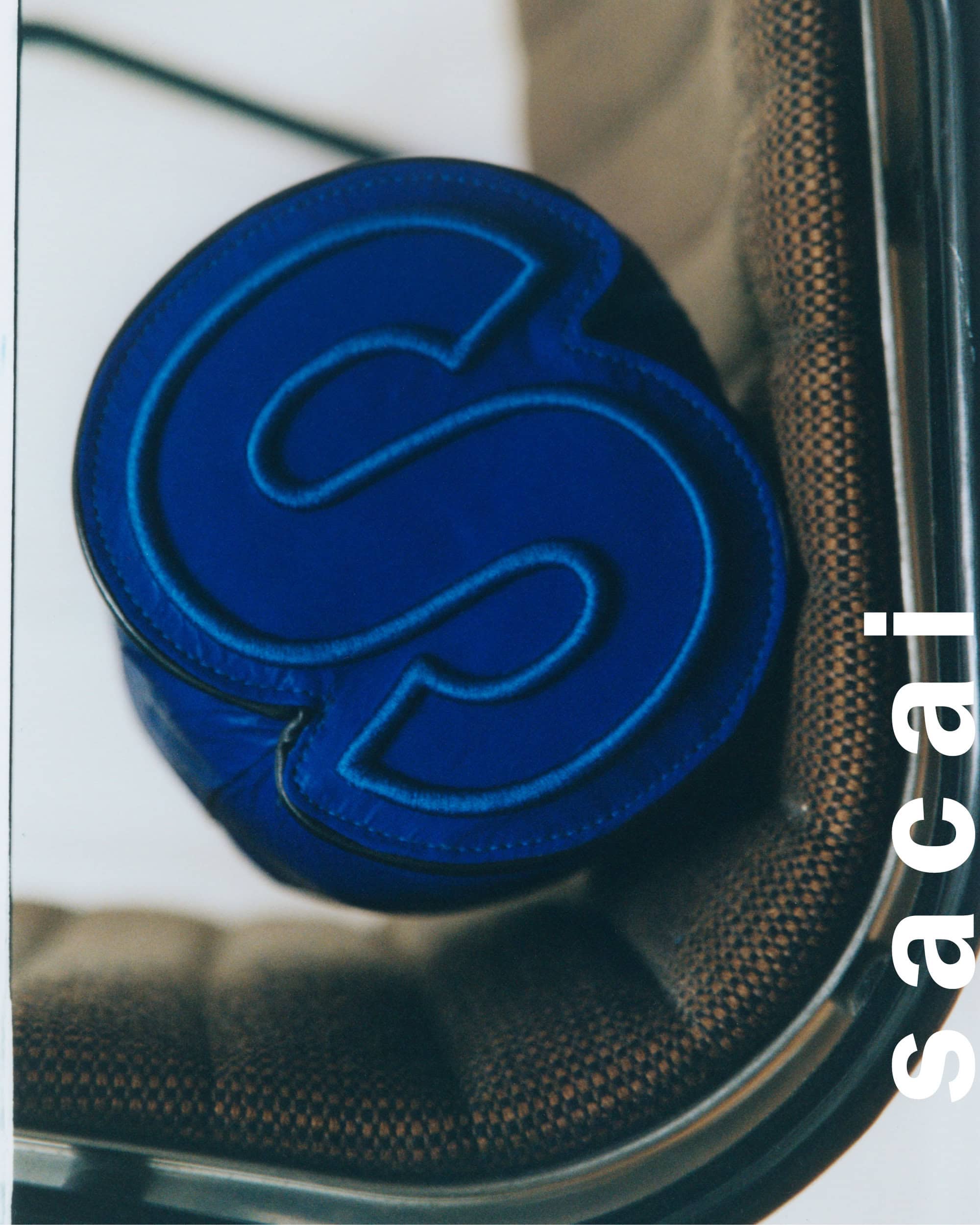 Close-up of a blue S-shaped cylindrical pillow resting on a brown patterned office chair with a metallic frame.