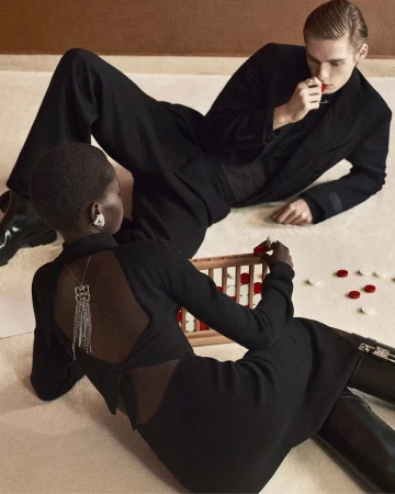 Two models in black outfits playing a game on a light carpet background for a Givenchy campaign