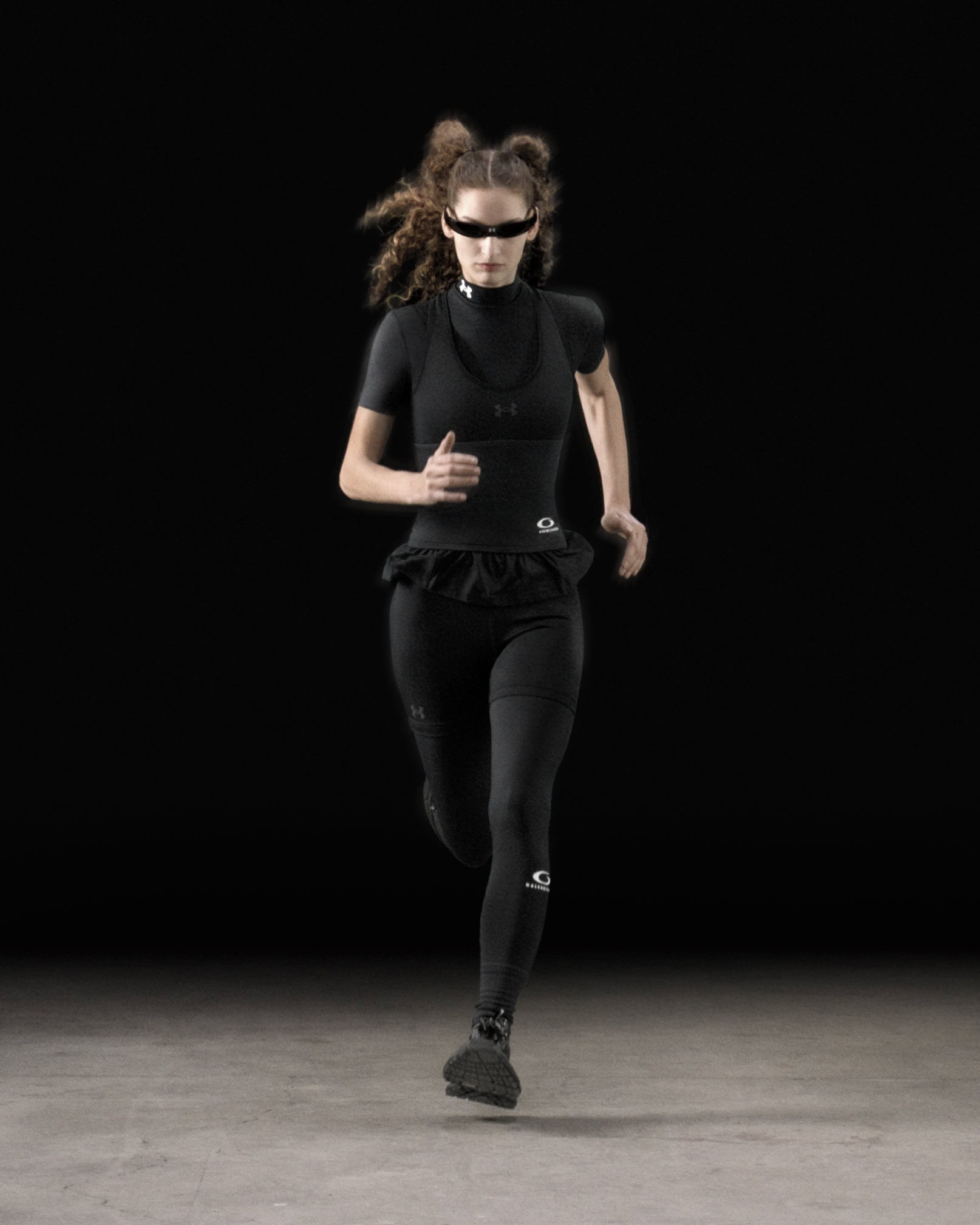 Female runner wearing black athletic gear and futuristic sunglasses sprinting against a dark background