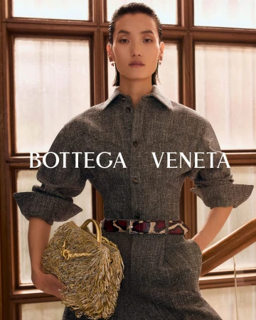 Model in grey tweed shirt dress holding a textured gold fringed handbag by Bottega Veneta